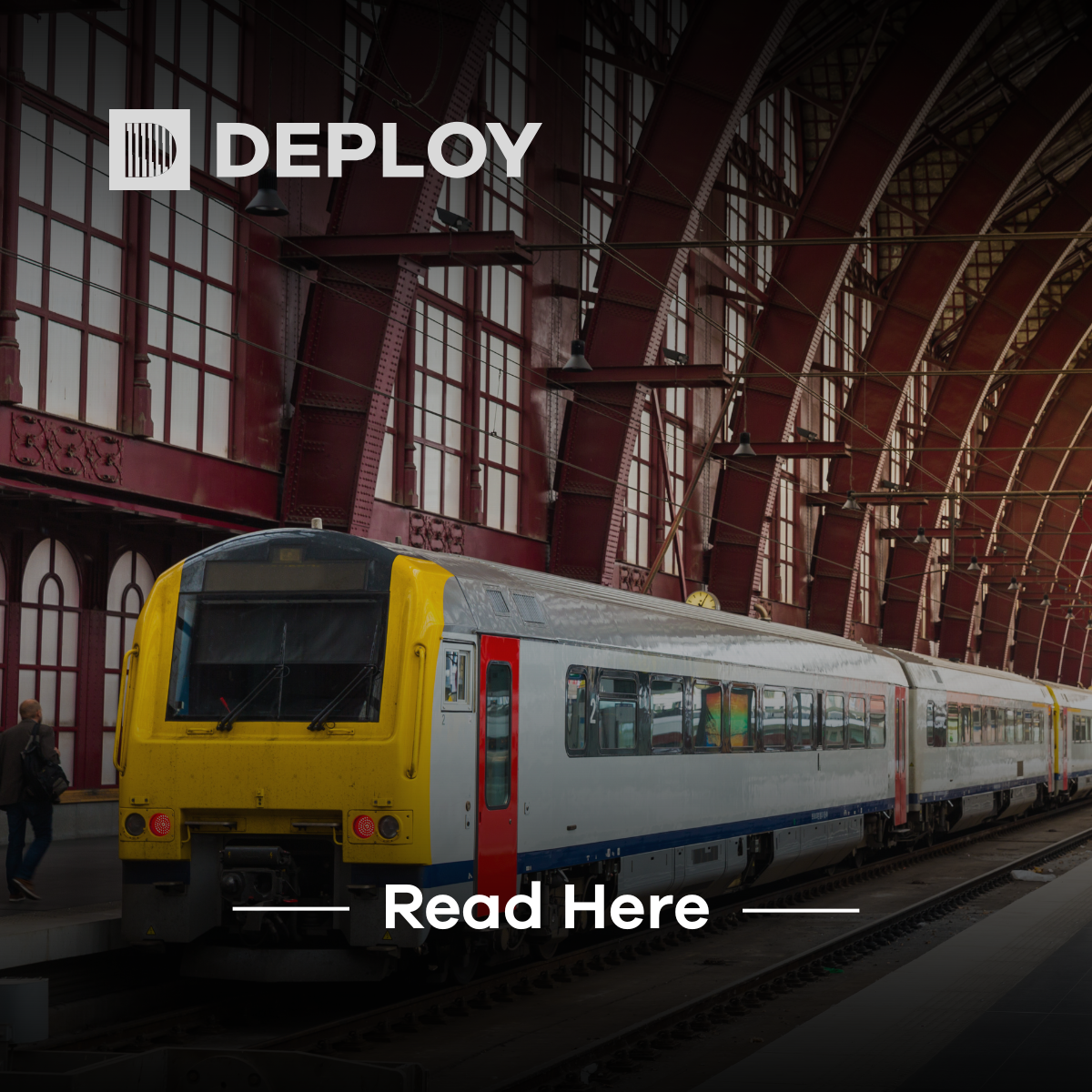 Train at a train station; yellow and white train car, red brick arches. 