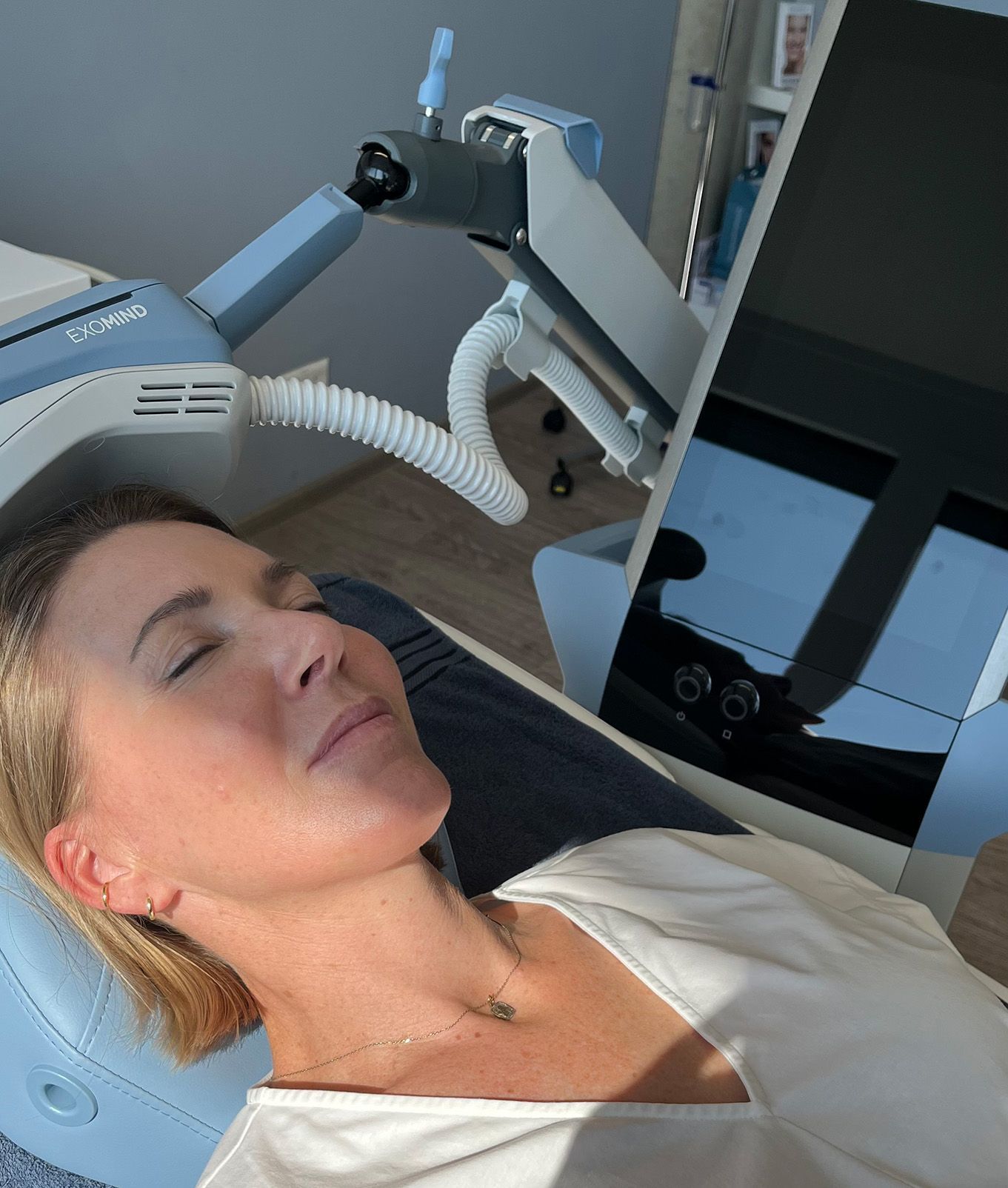Frau wird mit einem medizinischen Gerät mit EXOMIND behandelt, die Augen geschlossen, liegend