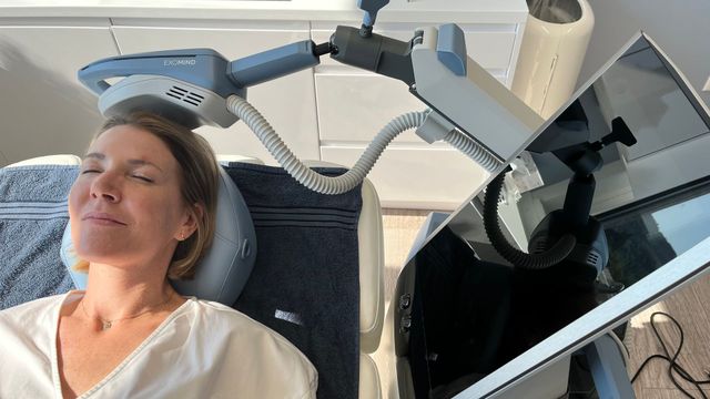 Frau erhält transkranielle Magnetstimulationstherapie; Gerät über dem Kopf bei EXOMIND-Therapie.