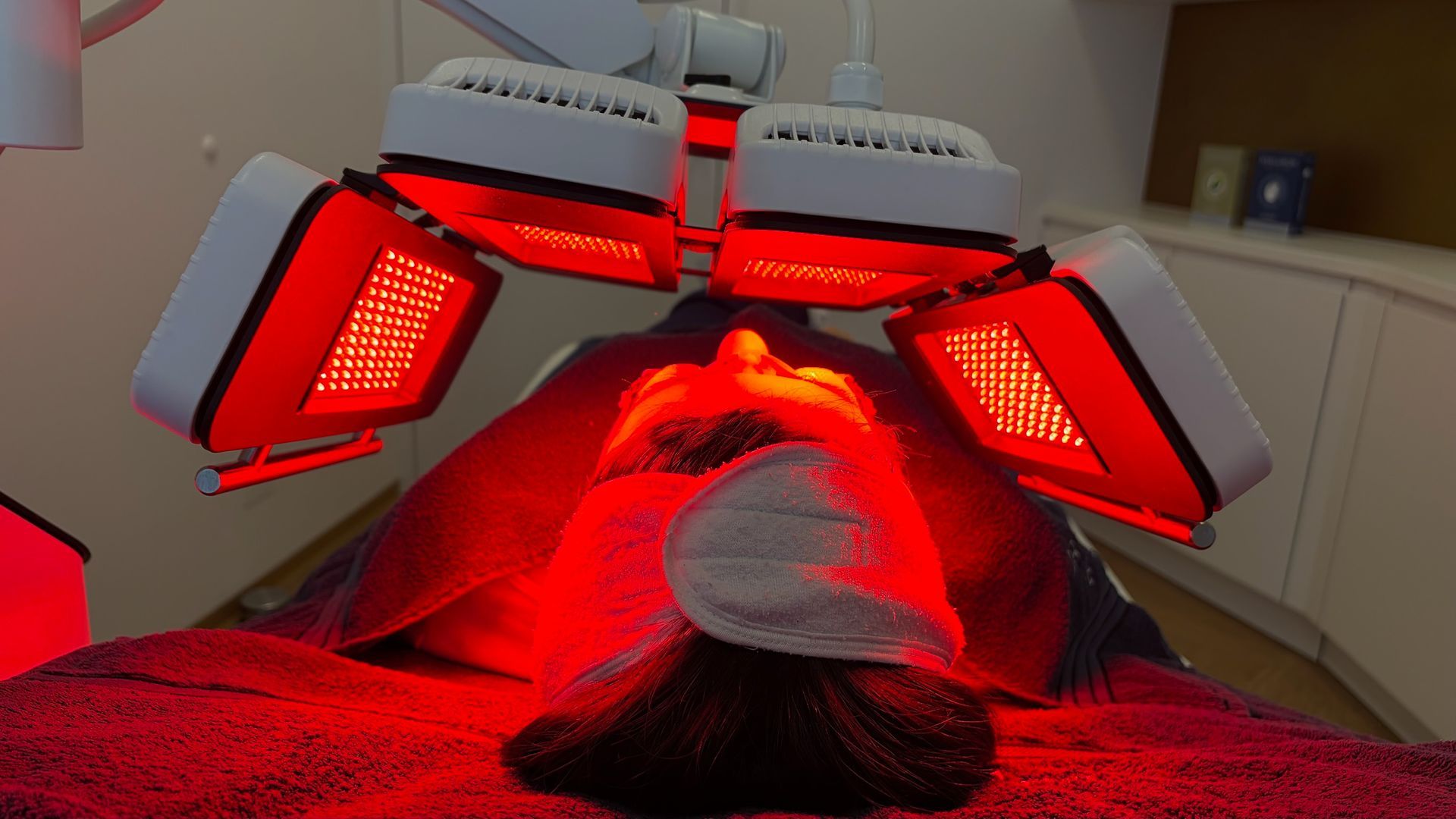 Frau erhält in einer Klinik eine Rotlichttherapie mit Schutz über den Augen.