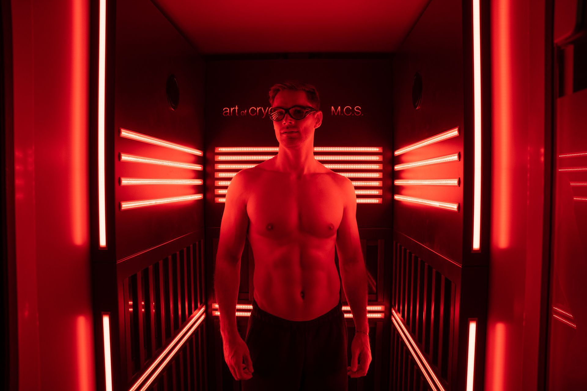 Mann mit Schutzbrille und ohne Hemd in einem rot beleuchteten Raum bei einer MCS-Therapie