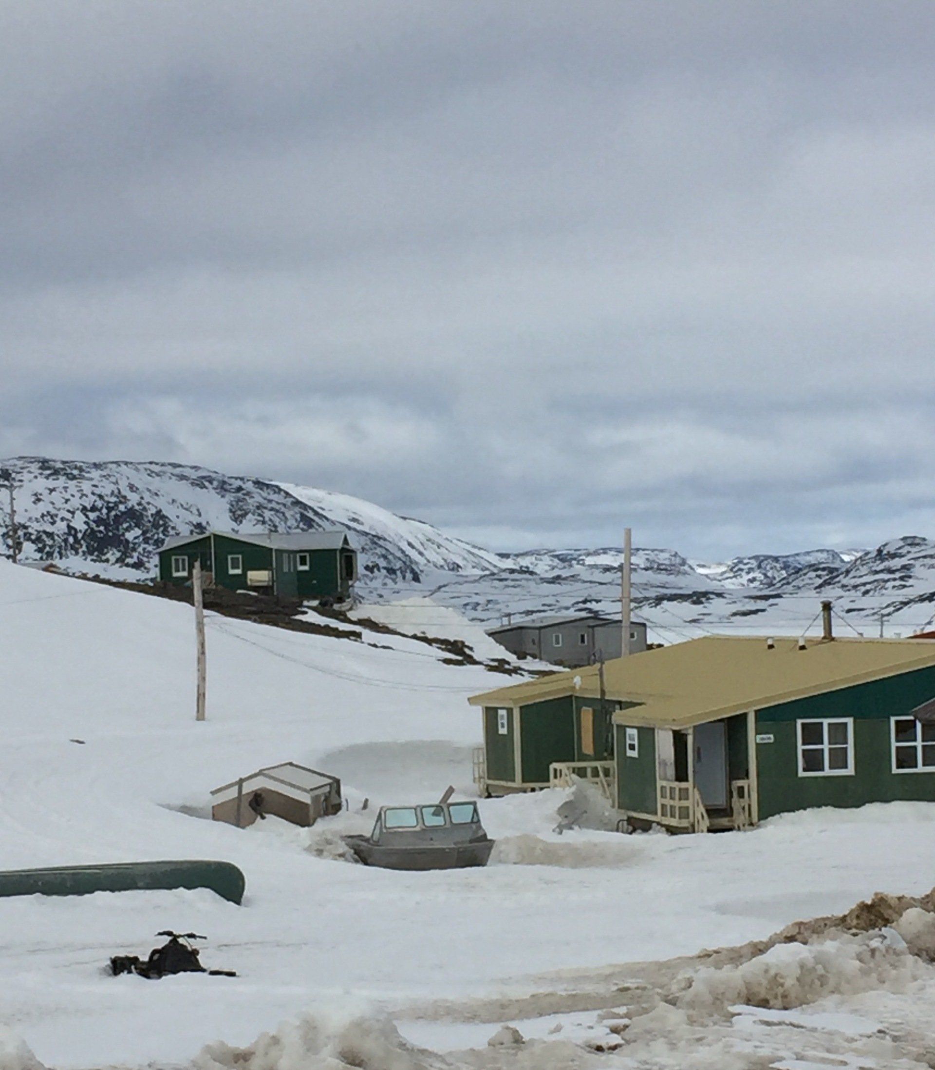 Ein grünes Haus im Schnee mit Bergen im Hintergrund