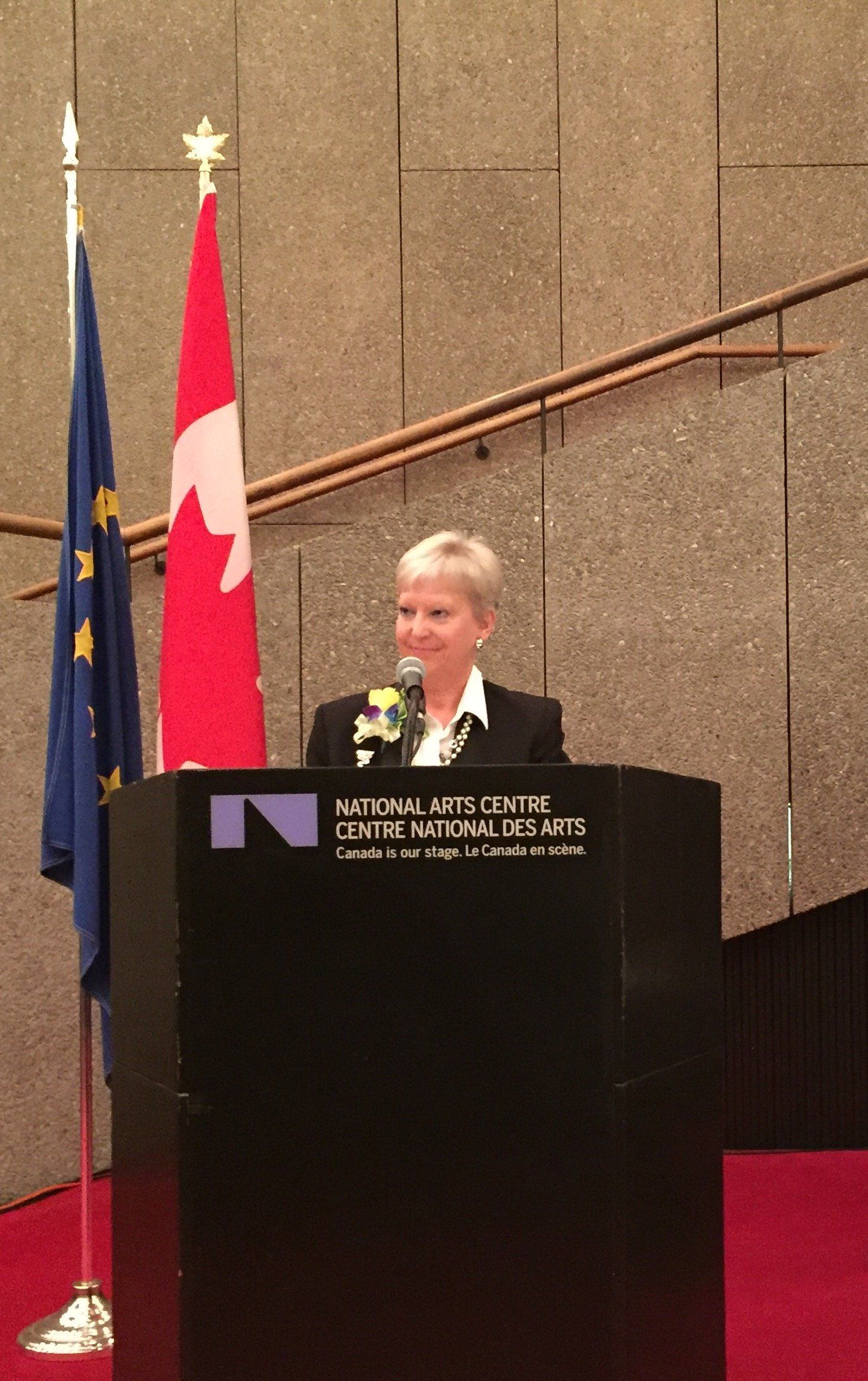 Eine Frau steht auf einem Podium vor einer kanadischen Flagge