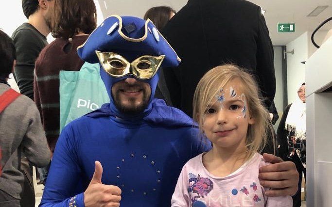 Ein Mann in einem blauen Kostüm posiert mit einem kleinen Mädchen für ein Foto.