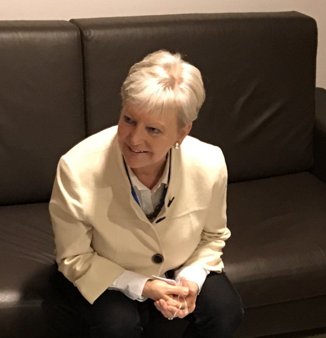 Eine Frau in einer weißen Jacke sitzt auf einer schwarzen Couch