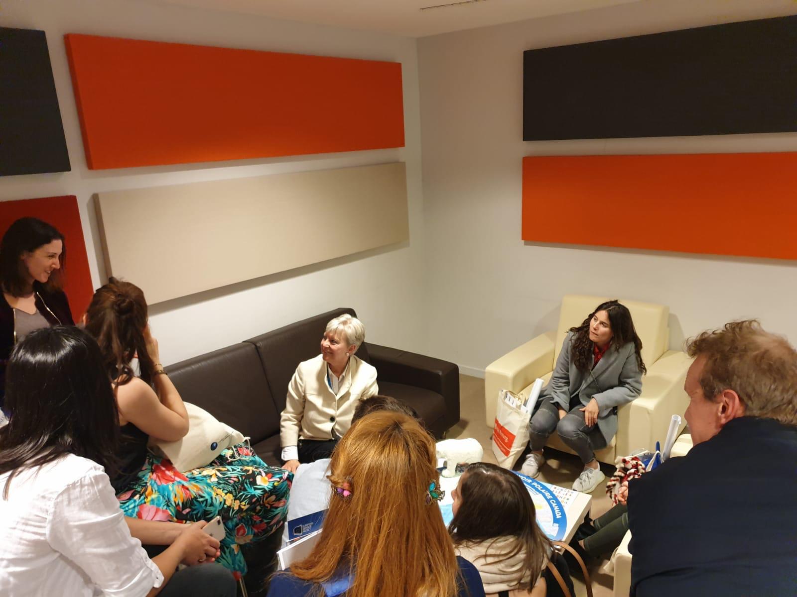 Eine Gruppe von Menschen sitzt um einen Tisch in einem Wohnzimmer