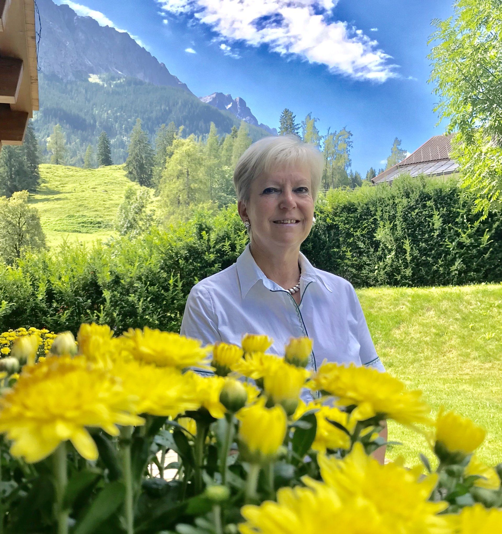 Eine Frau in einem weißen Hemd steht vor gelben Blumen