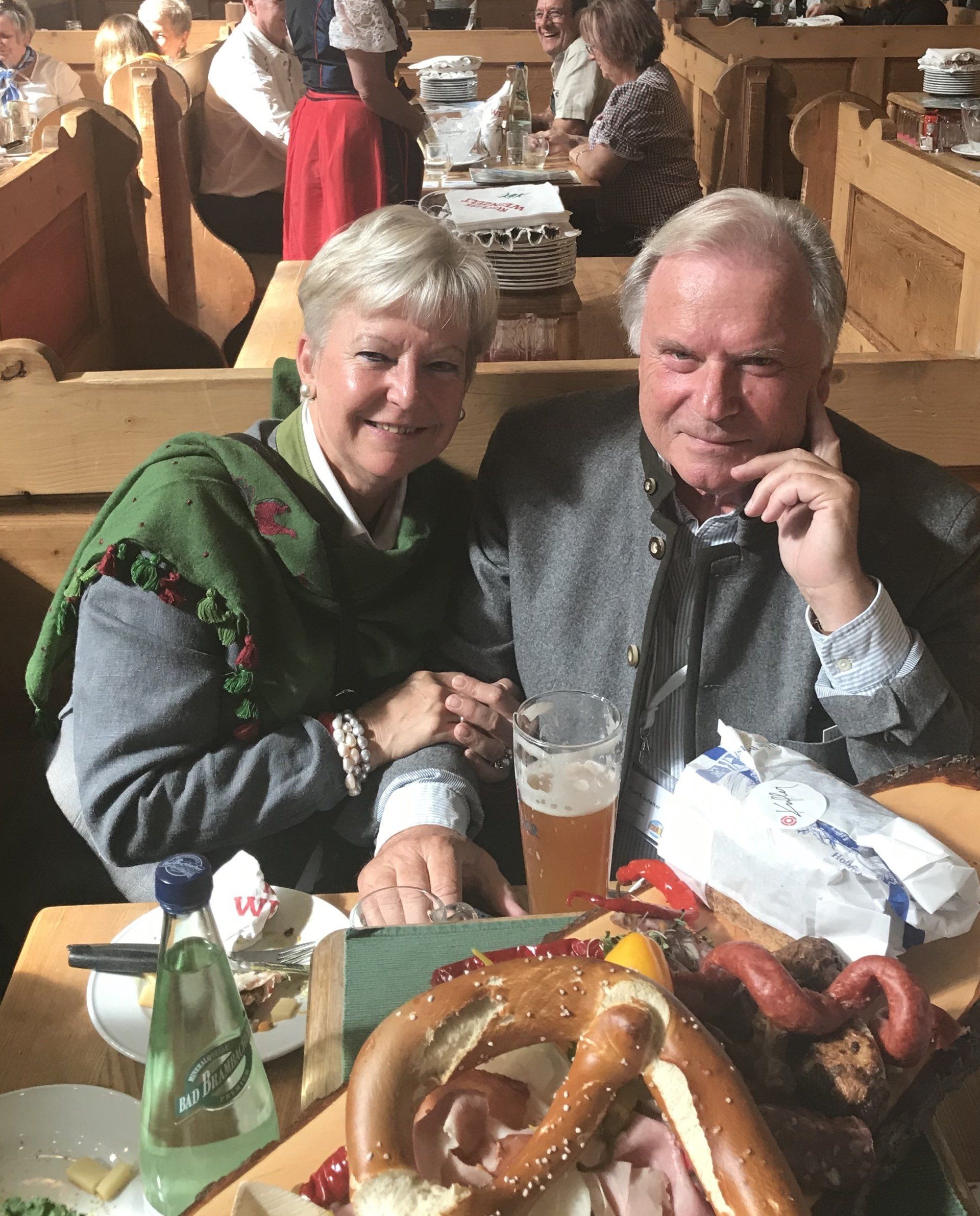 Ein Mann und eine Frau sitzen mit Essen und einem Glas Bier an einem Tisch.
