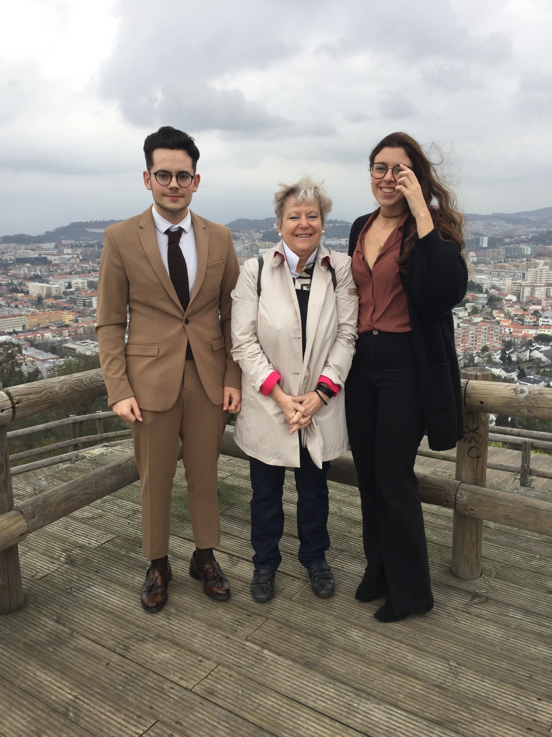 Ein Mann in Anzug und Krawatte steht neben zwei Frauen.