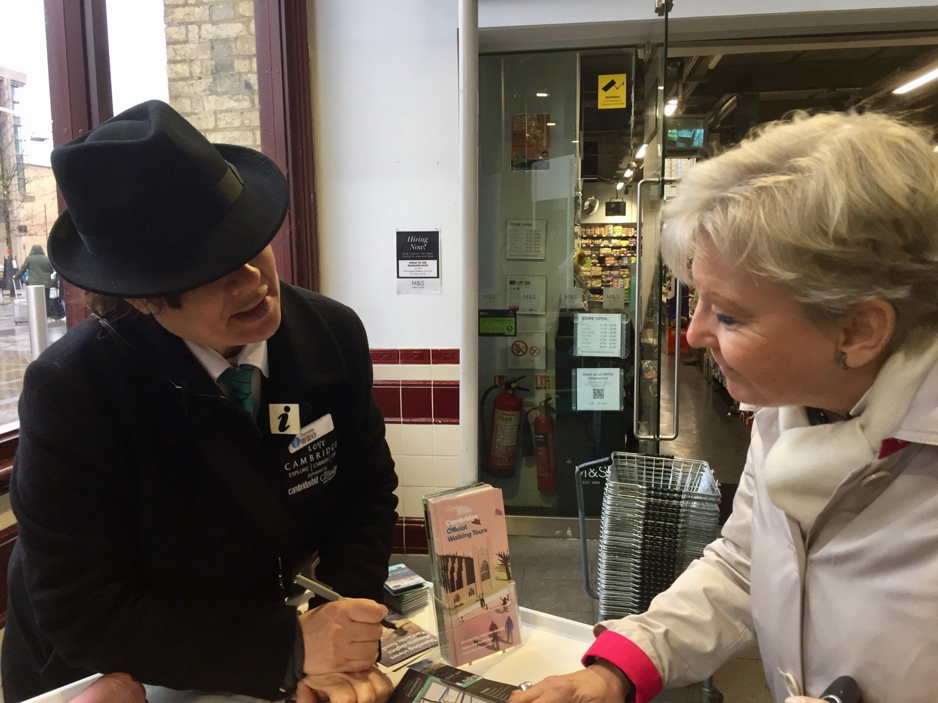 Ein Mann mit Hut spricht mit einer Frau in einem Geschäft.
