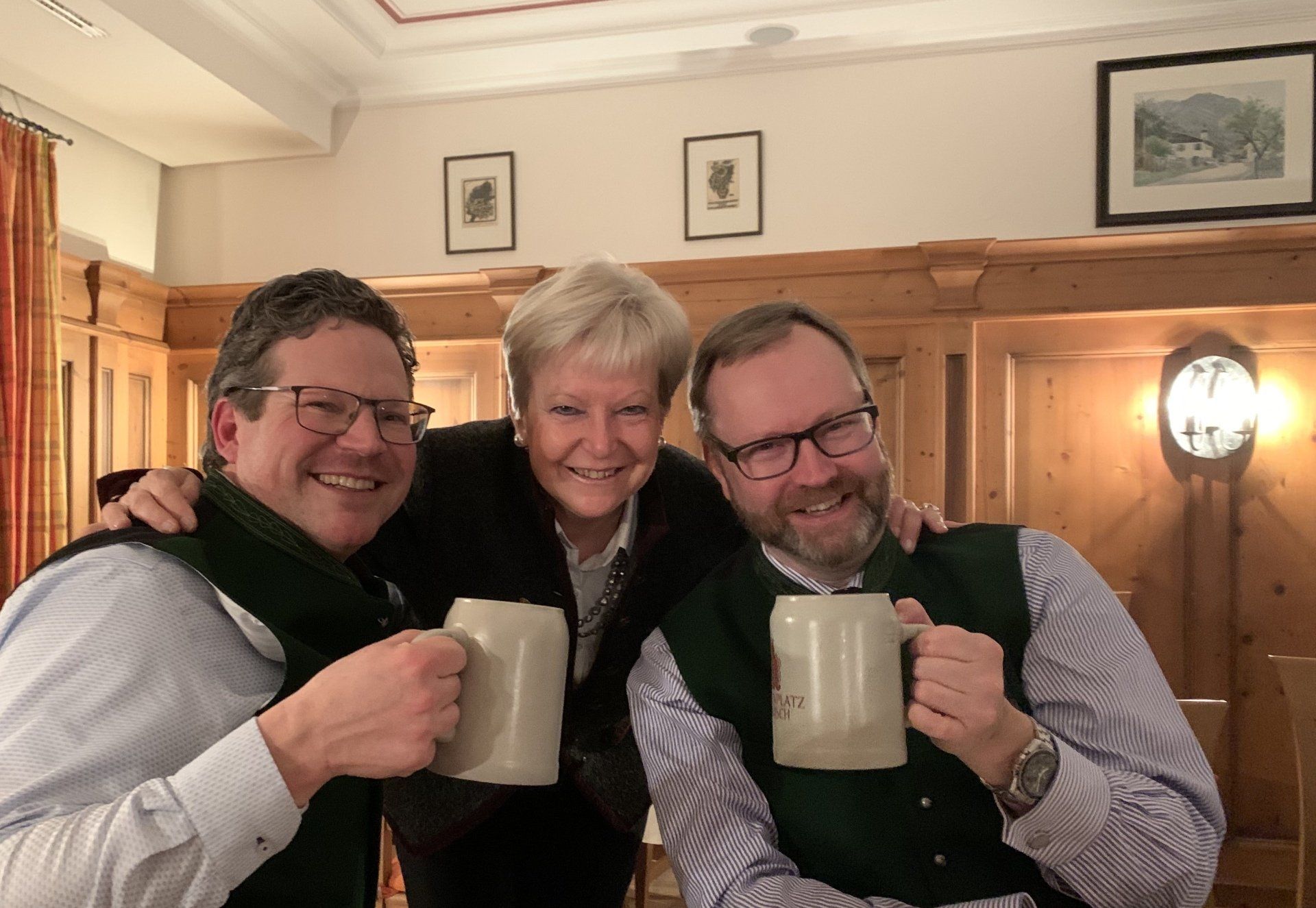 Drei Männer und eine Frau posieren für ein Foto, während sie Krüge Bier halten