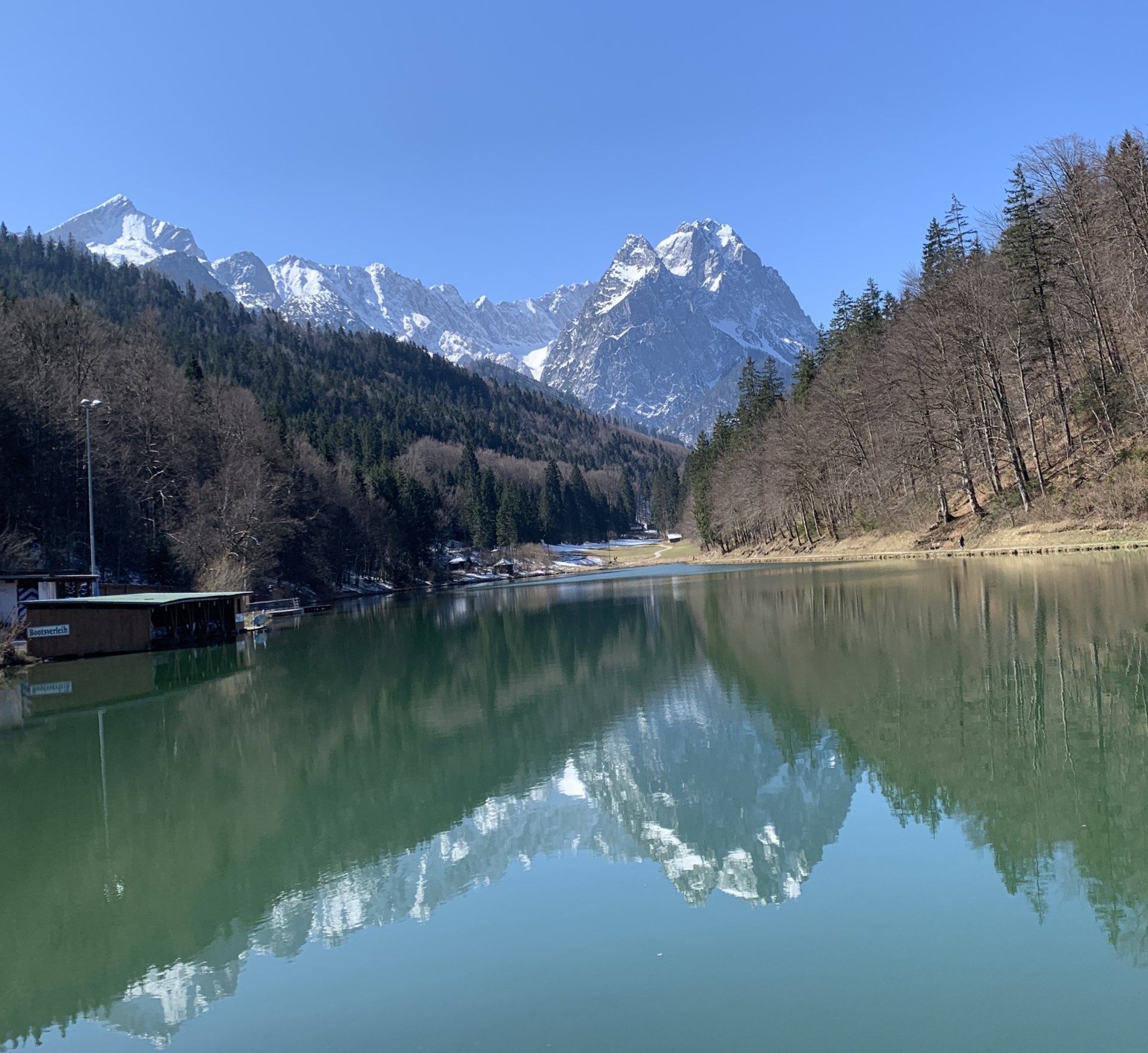 Ein See mit Bergen im Hintergrund und Bäumen am Ufer
