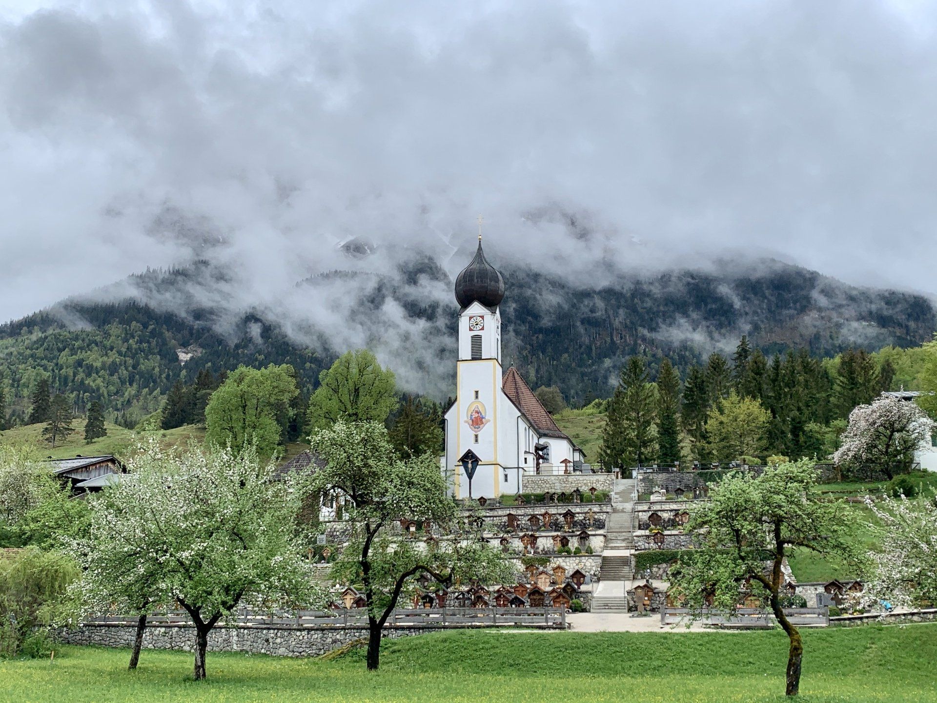 Inmitten eines Feldes steht eine Kirche mit Bergen im Hintergrund.
