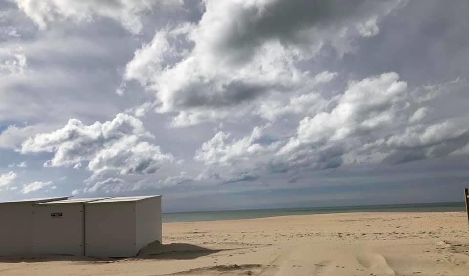 Ein paar weiße Gebäude an einem Strand mit einem bewölkten Himmel im Hintergrund.