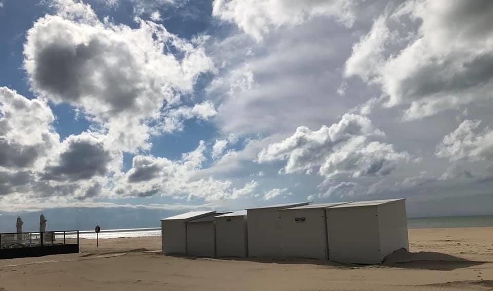 Eine Reihe von Strandhütten an einem bewölkten Tag an einem Strand.