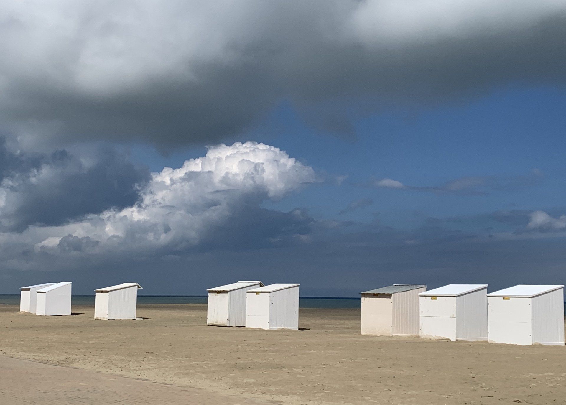 Eine Reihe weißer Strandhütten an einem bewölkten Tag