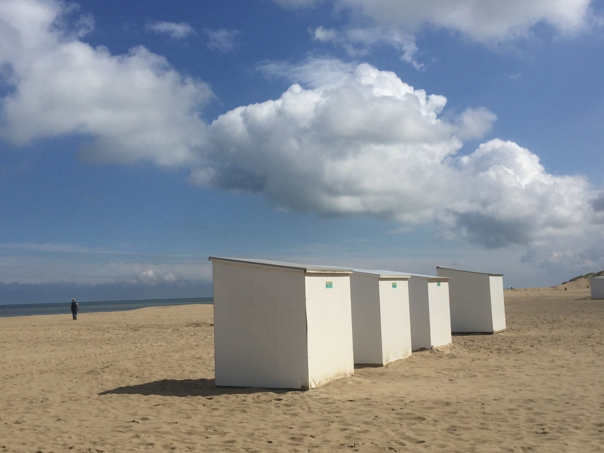 Eine Reihe weißer Strandhütten an einem Sandstrand