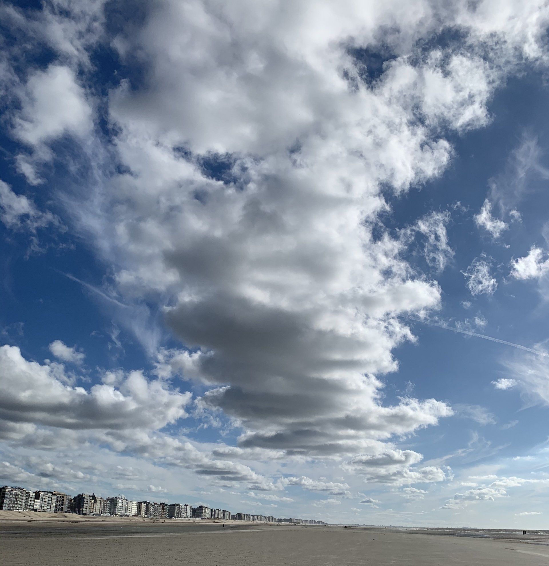 Ein bewölkter Himmel über einem Strand mit Gebäuden in der Ferne