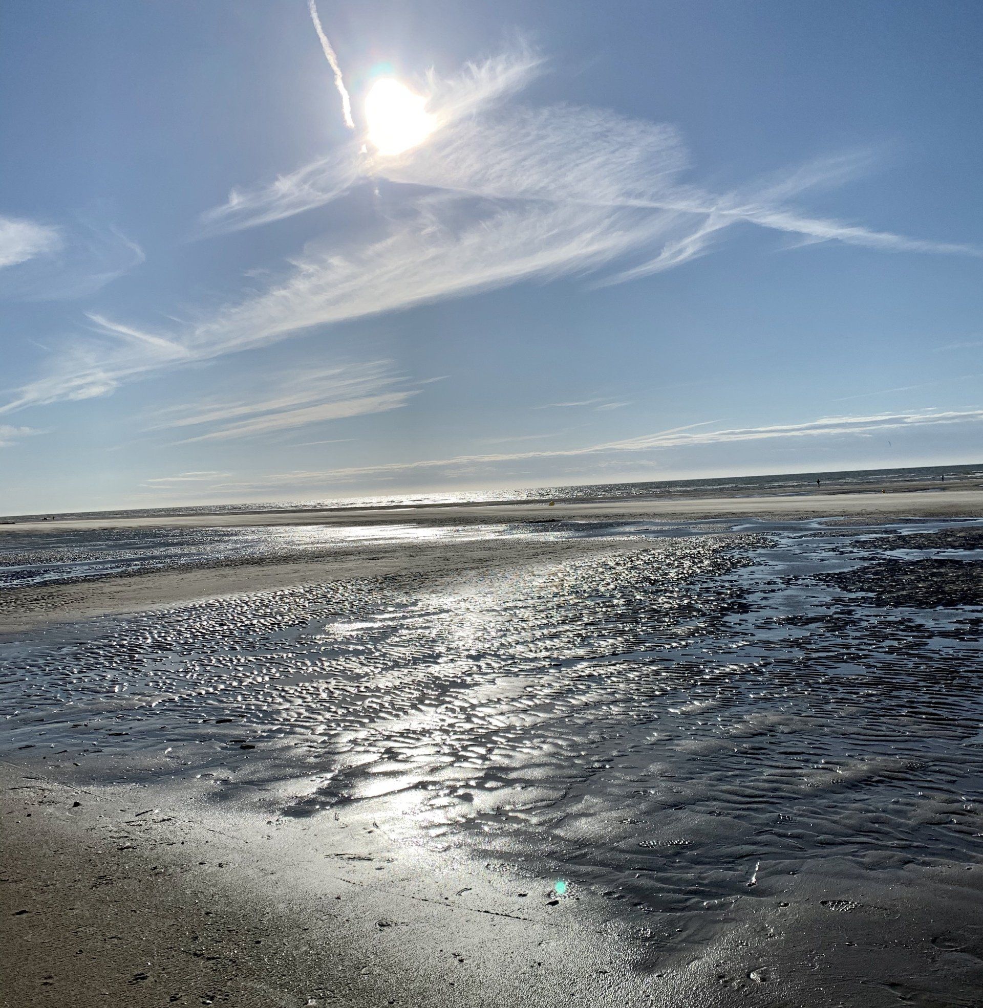 Die Sonne scheint durch die Wolken über dem Strand