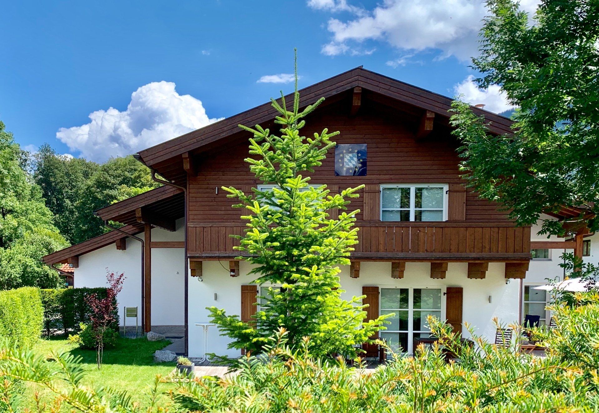 Ein großes Haus mit einem Holzdach ist von Bäumen und Büschen umgeben