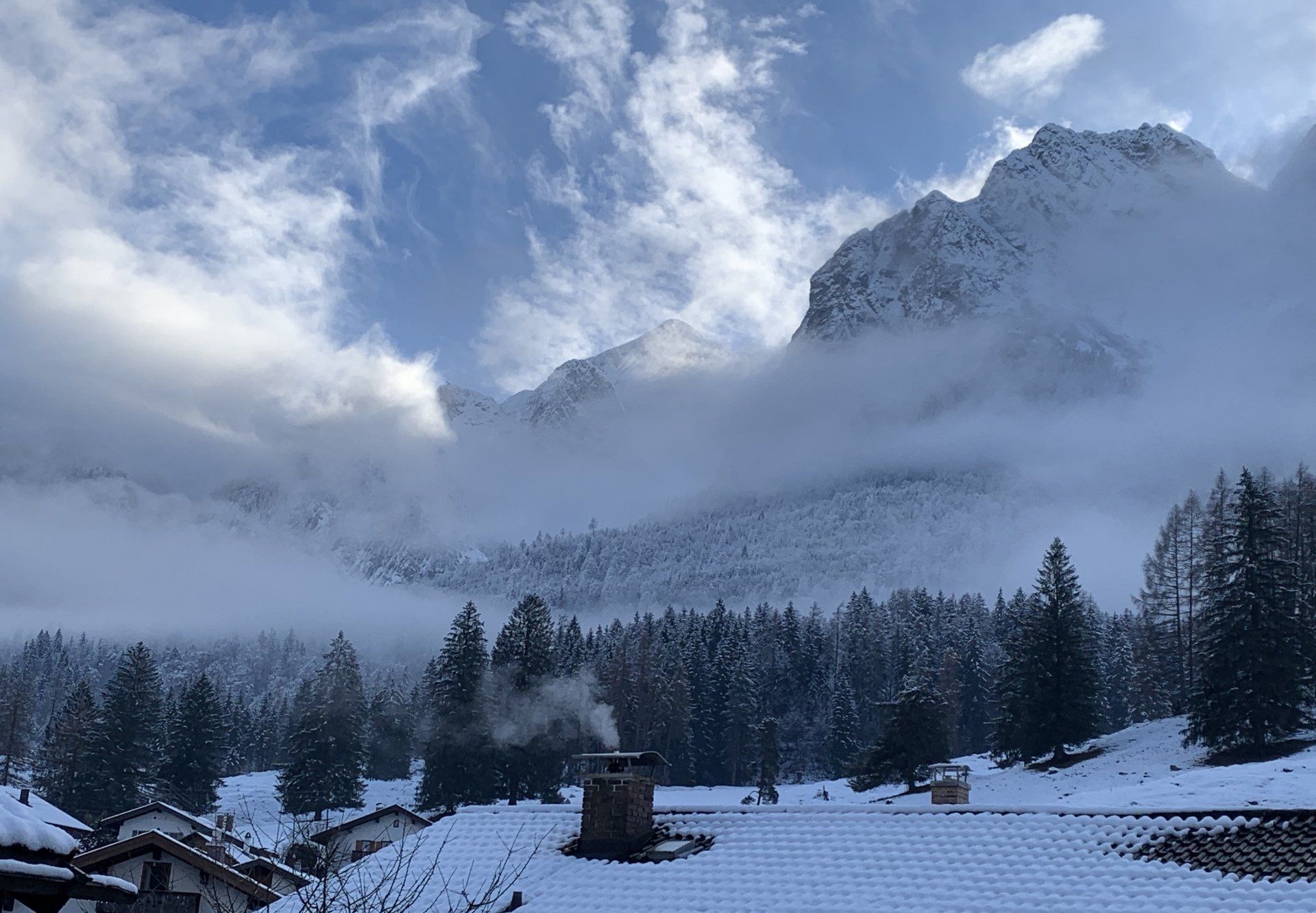 Eine verschneite Landschaft mit einem Schornstein im Vordergrund und einem Berg im Hintergrund.