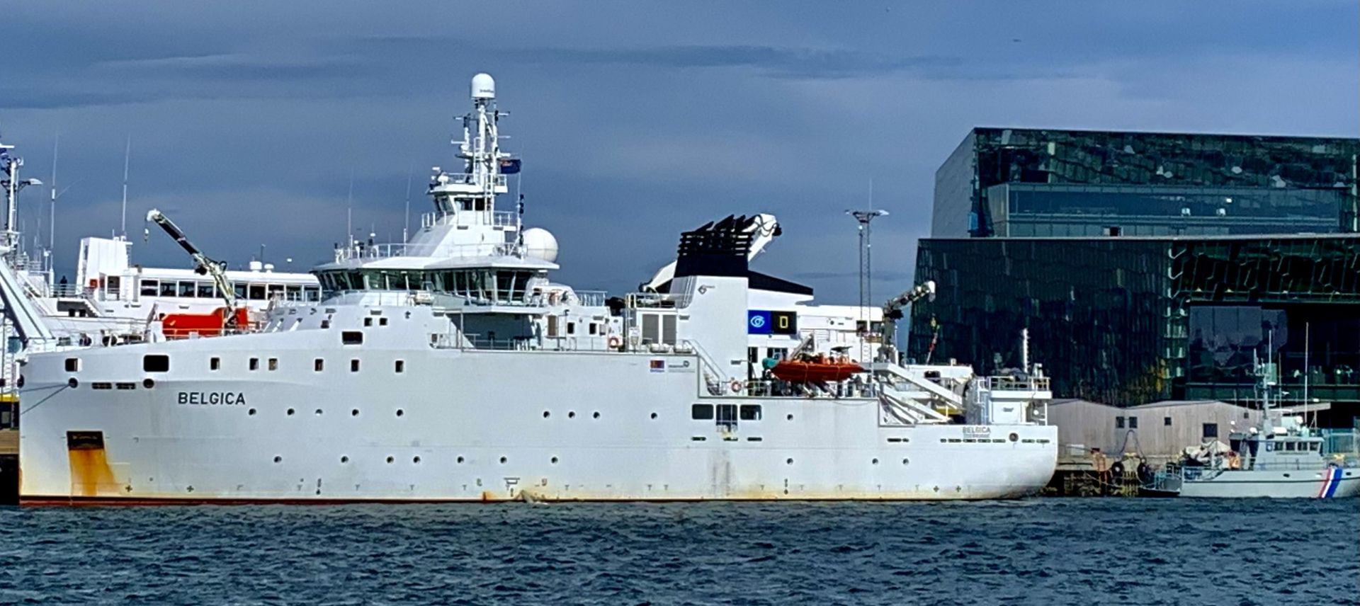 Eine Collage aus Fotos zeigt einen Mann und eine Frau, die an einem Tisch vor einem Schild mit der Aufschrift „Ministerial