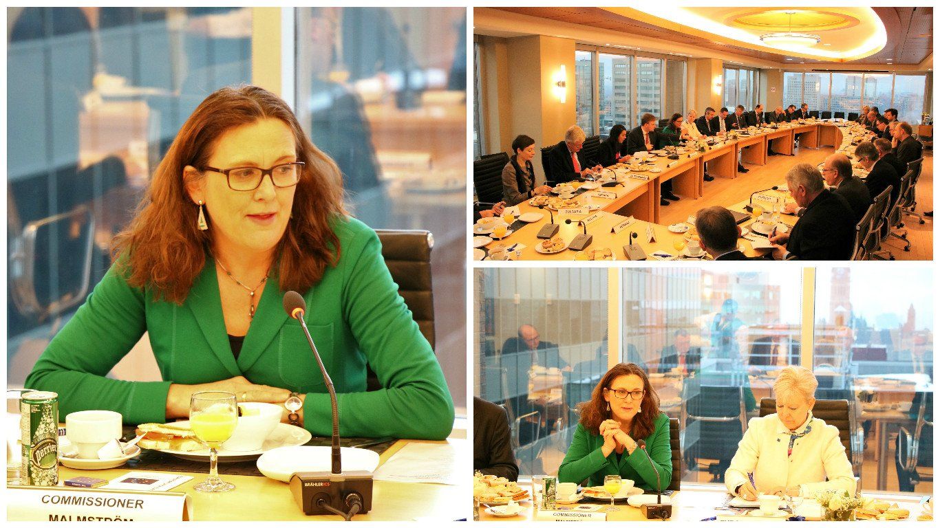 Eine Frau in einer grünen Jacke sitzt mit einem Mikrofon an einem Tisch.