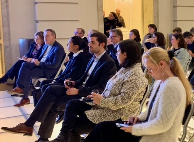 Eine Gruppe von Leuten sitzt auf Stühlen und schaut auf ihre Telefone