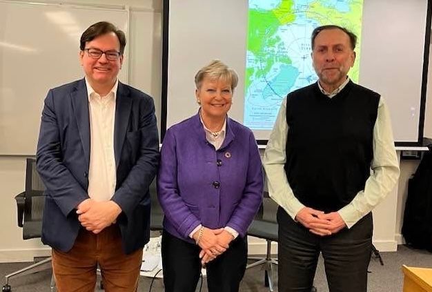 Drei Personen stehen nebeneinander in einem Raum.