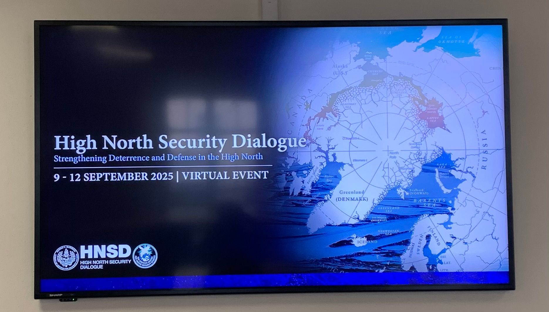 Ein Bildschirm mit Informationen zur Veranstaltung „High North Security Dialogue“ und einer Weltkarte, September 2025.