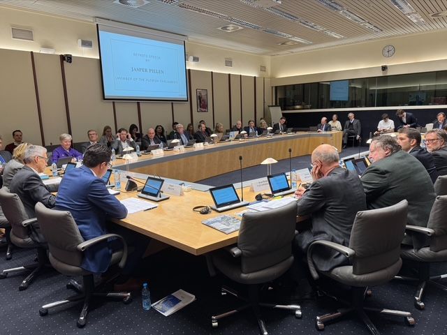 Eine Gruppe von Menschen sitzt in einem Konferenzraum um einen langen Tisch.