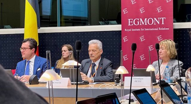 Eine Gruppe von Menschen sitzt an einem Tisch vor Mikrofonen.