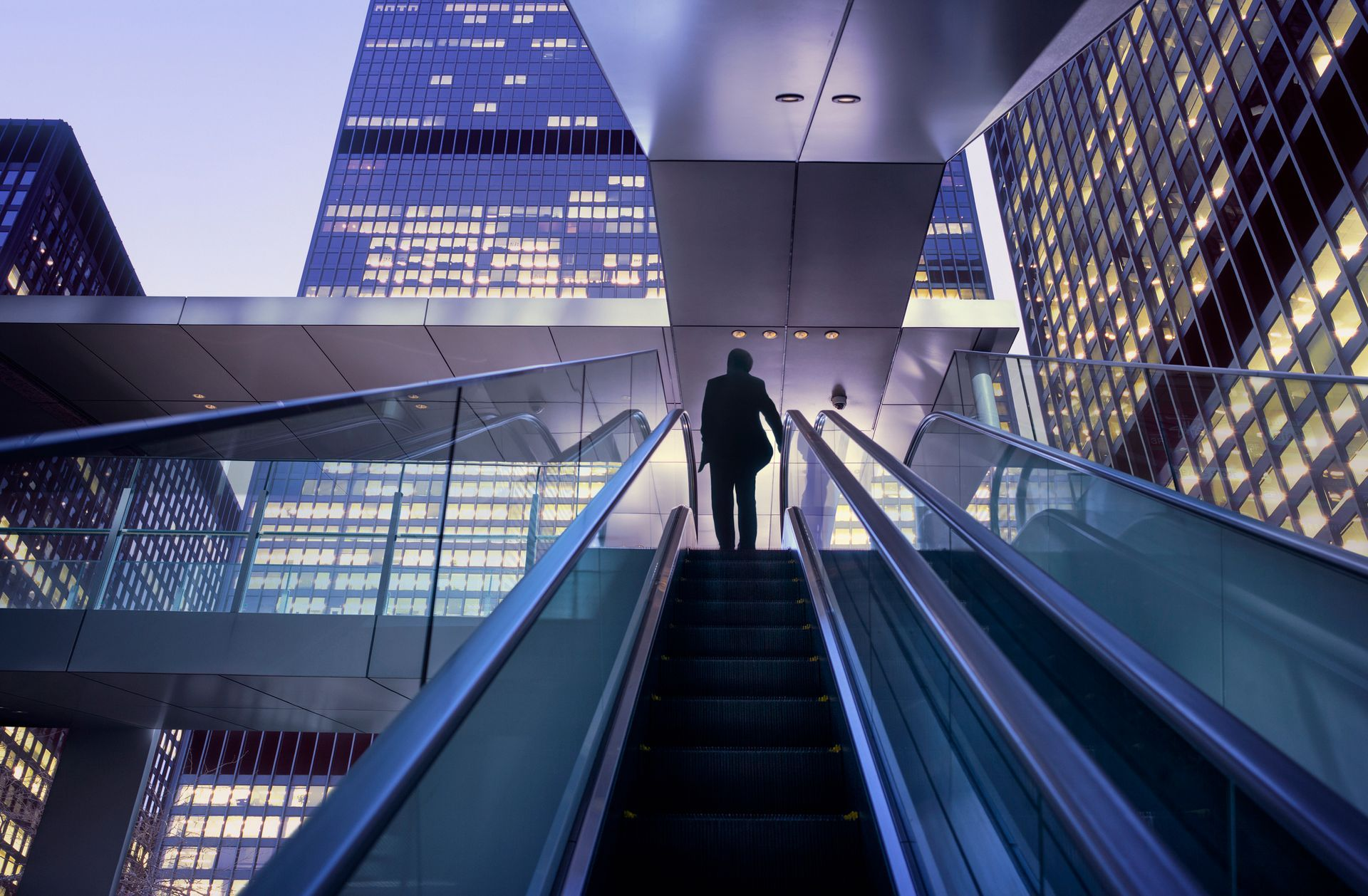 A man is walking up an escalator in a city at night