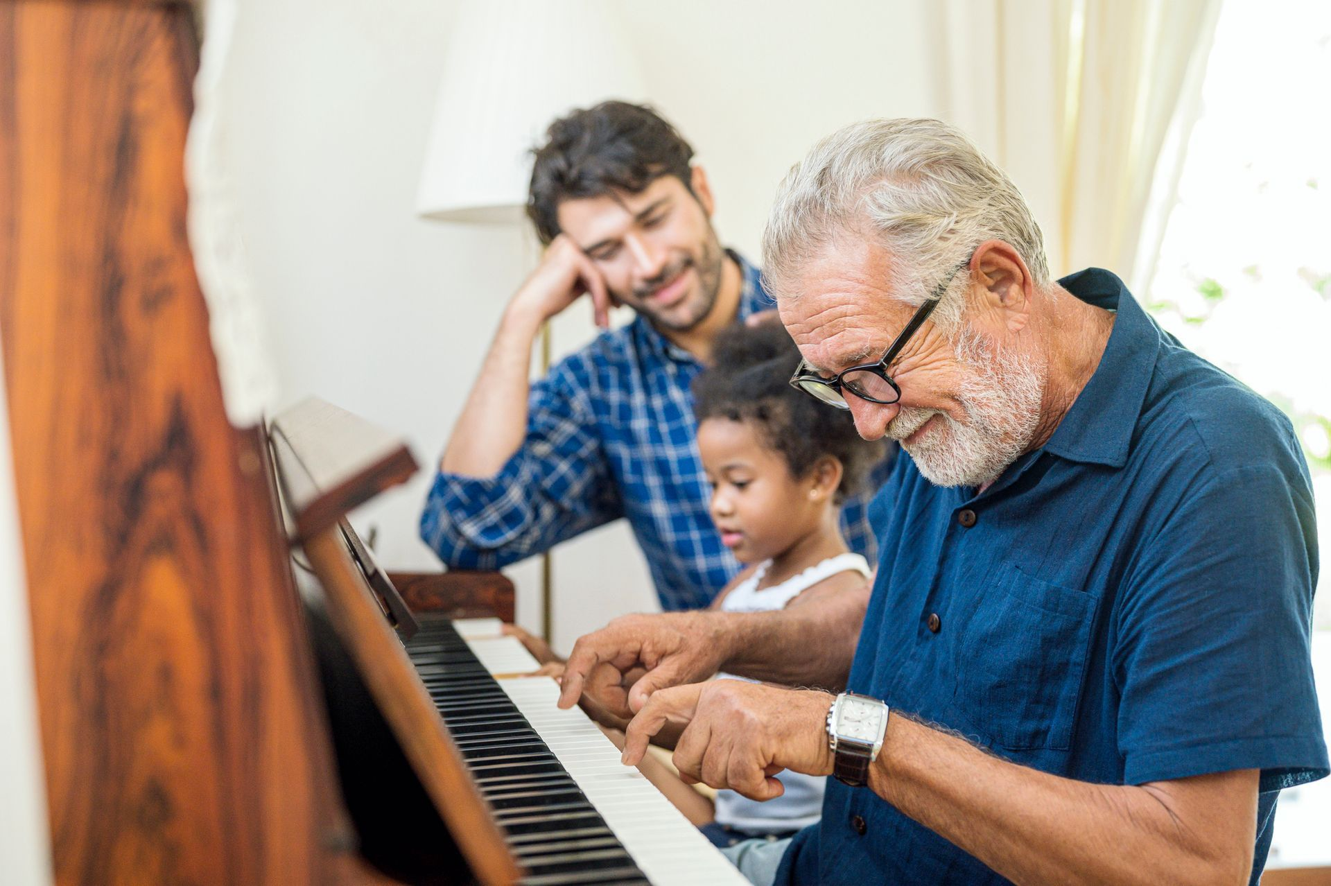 A man is teaching a little girl how to play the piano.