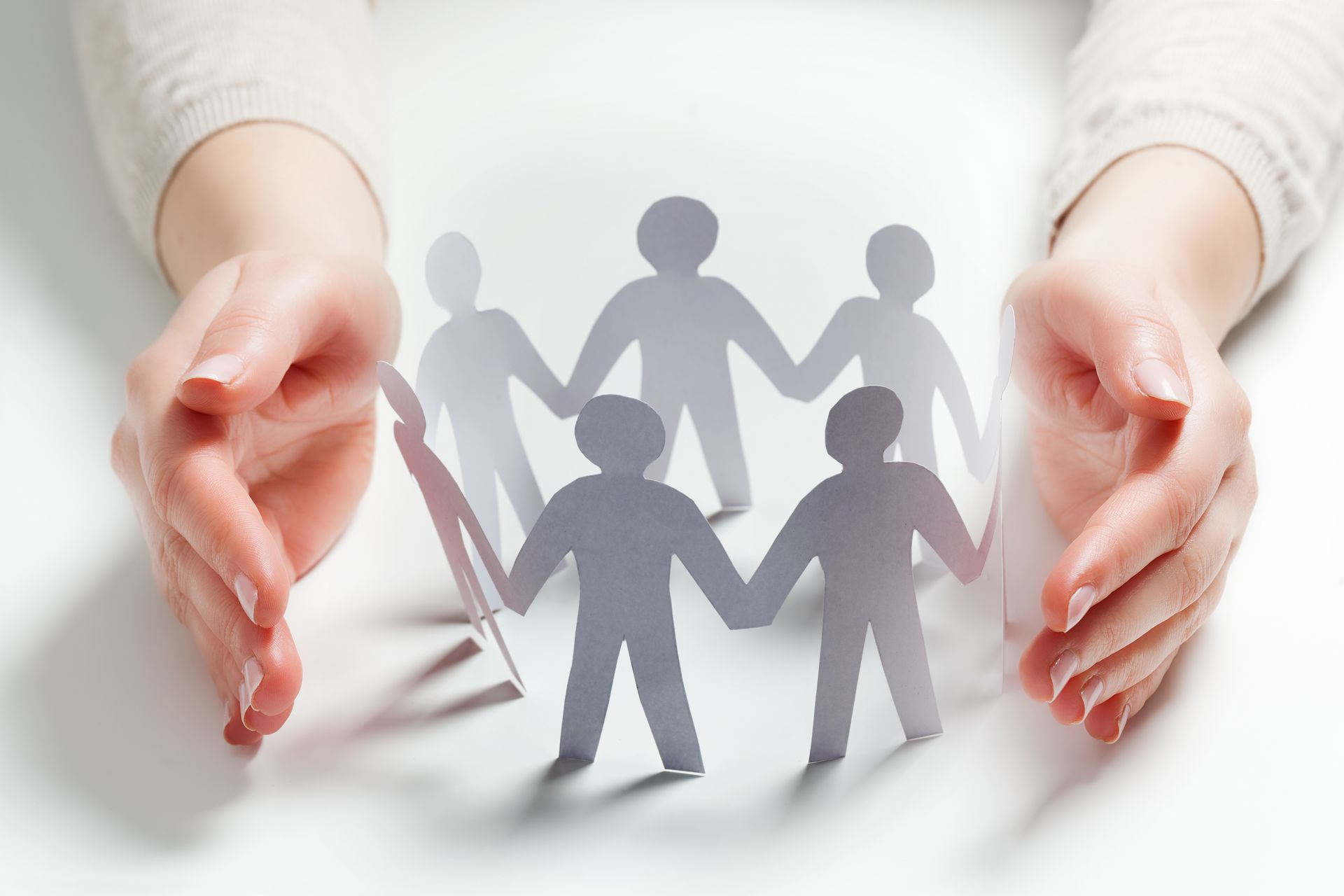 A person is holding a group of paper people holding hands