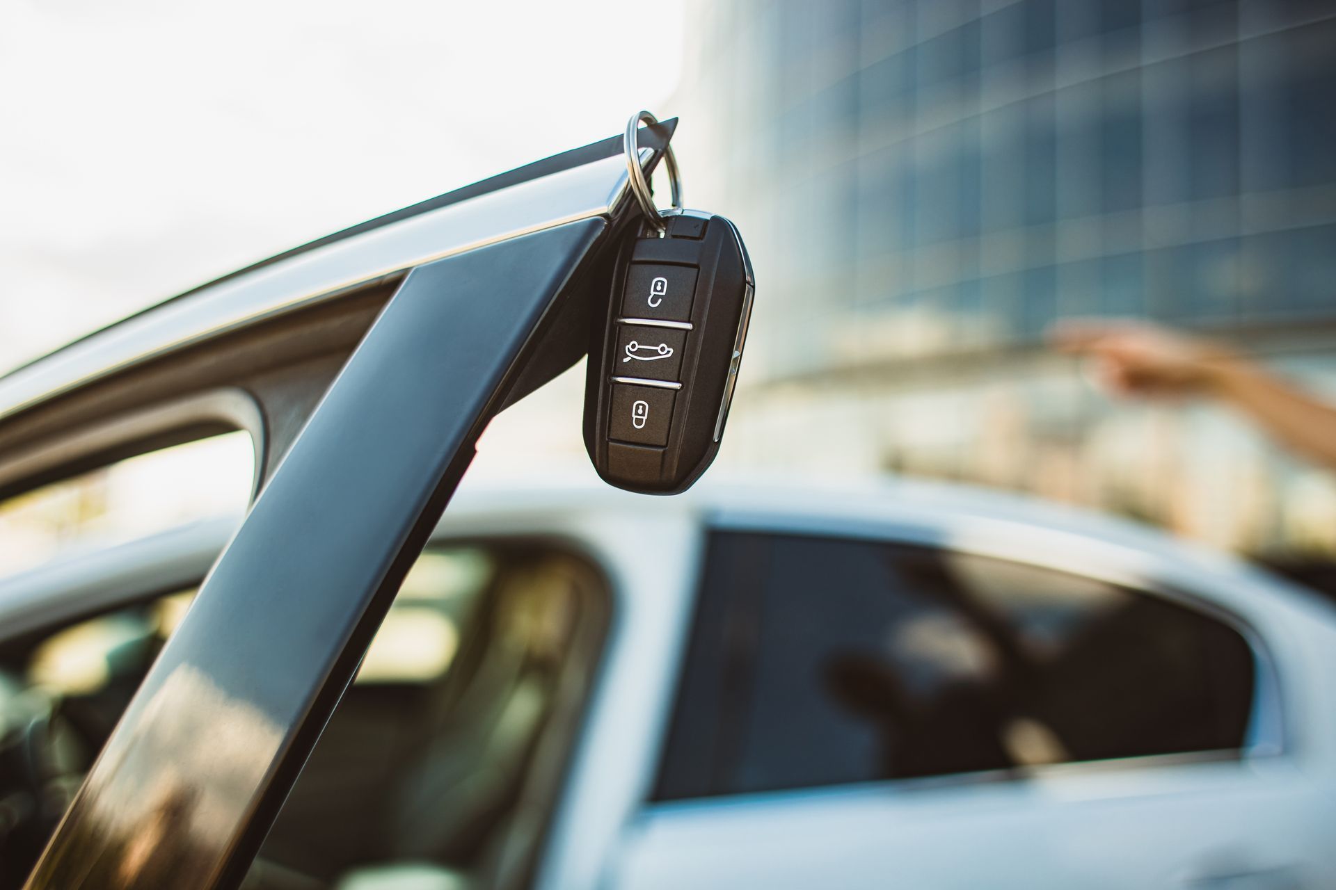 A car key is hanging from the door of a car.