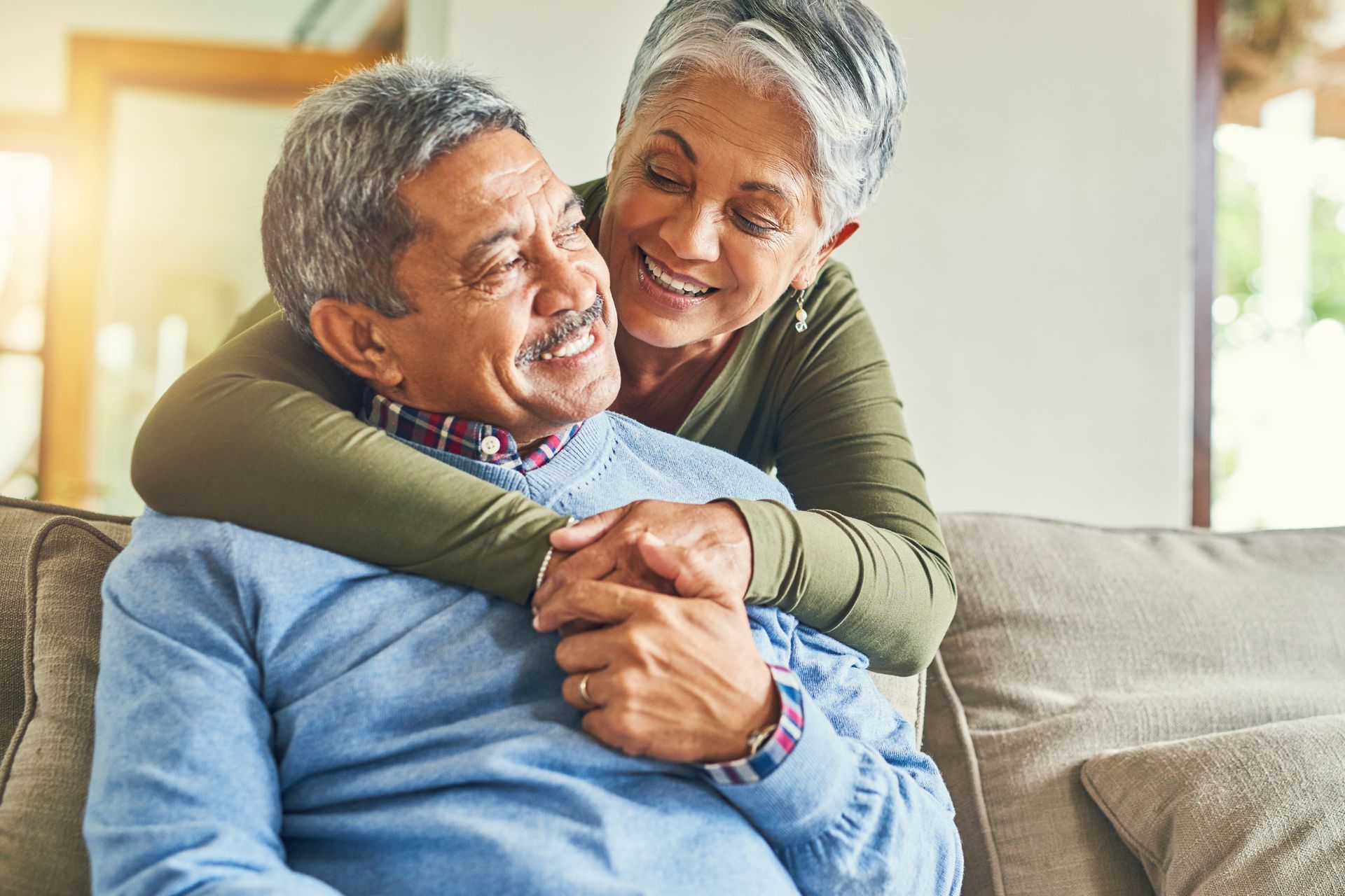 A woman is hugging a man while sitting on a couch.