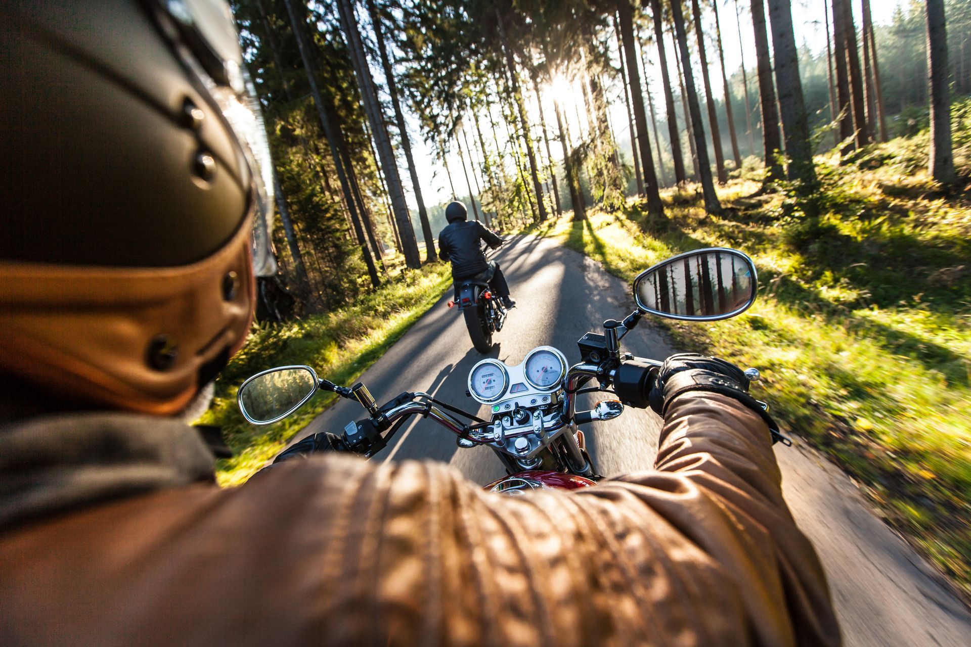 A man is riding a motorcycle down a forest road.