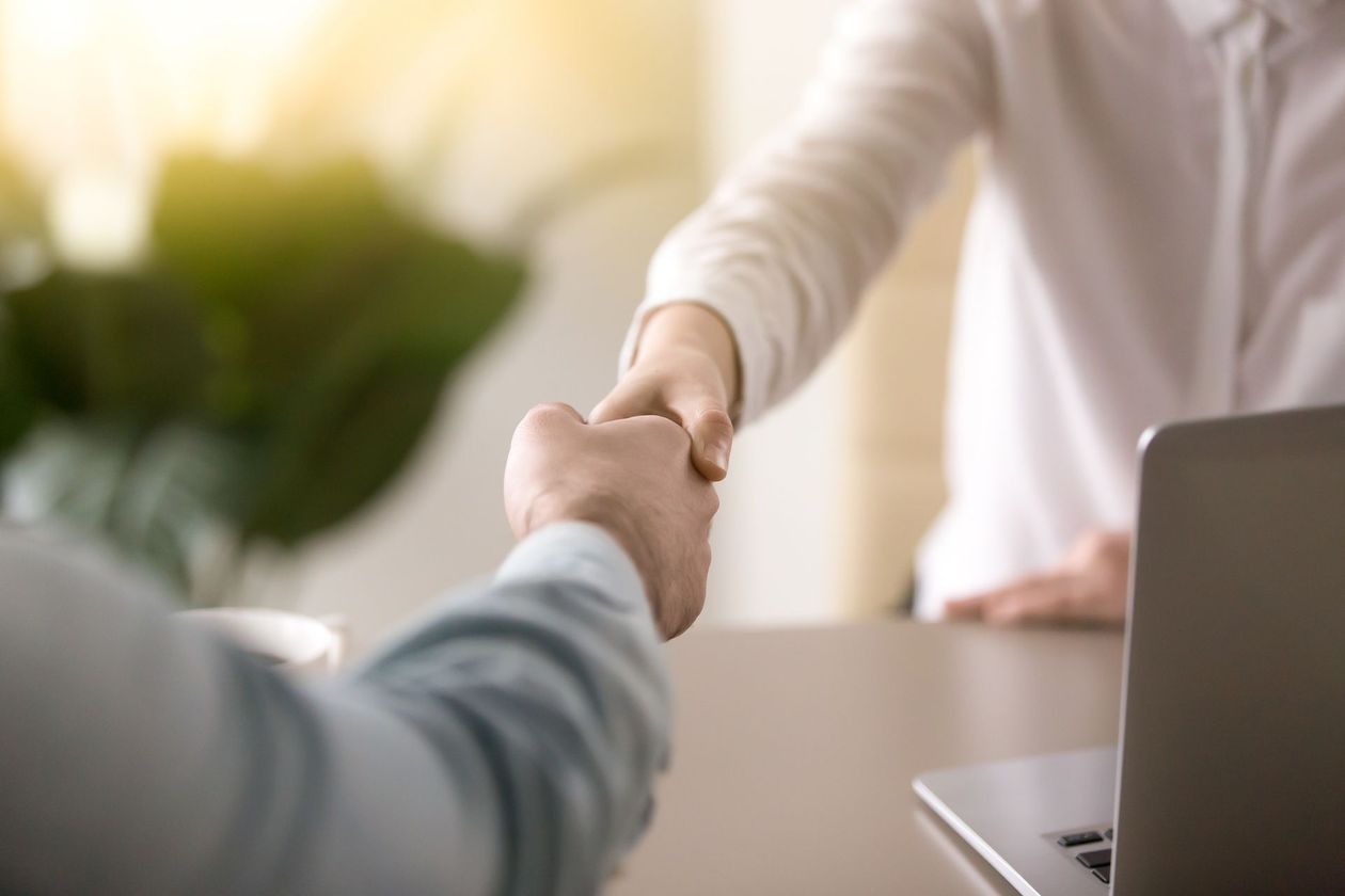 A man and a woman are shaking hands over a table.