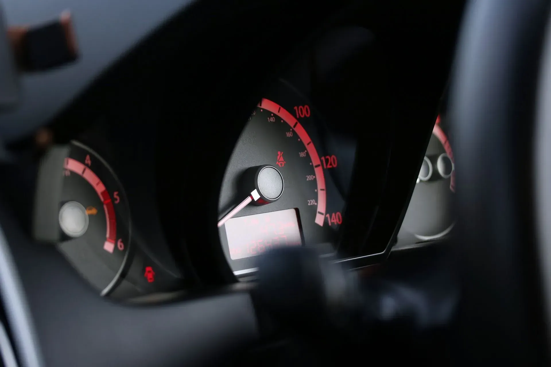 A close up of a car dashboard with red numbers