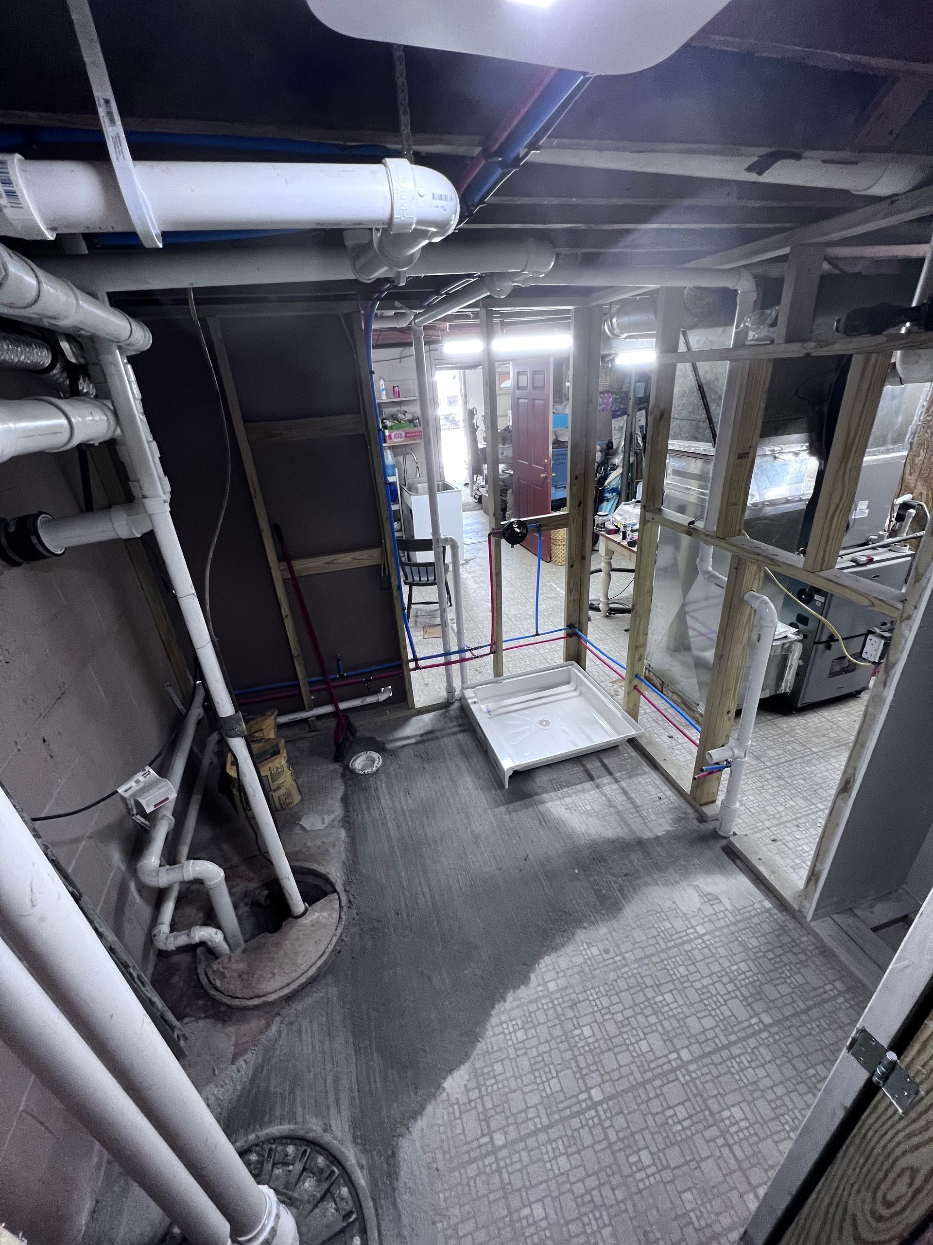 Basement with exposed pipes, concrete floor, wooden frames, and a small metal ramp.