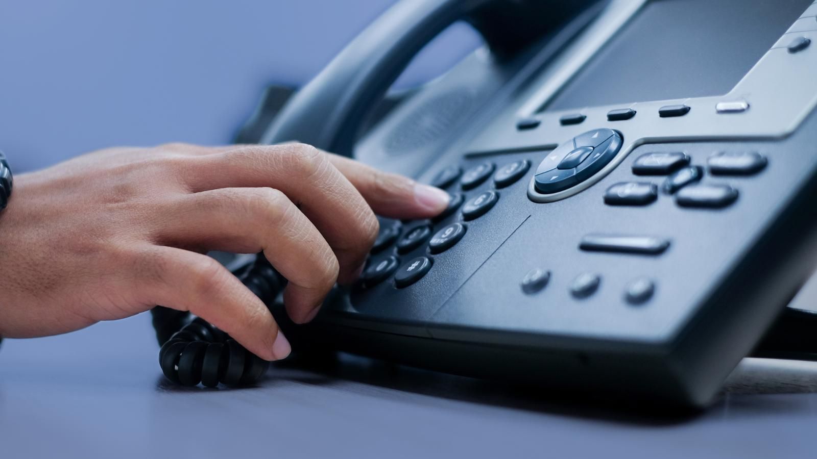 A close up of a person 's hand pressing a button on a telephone