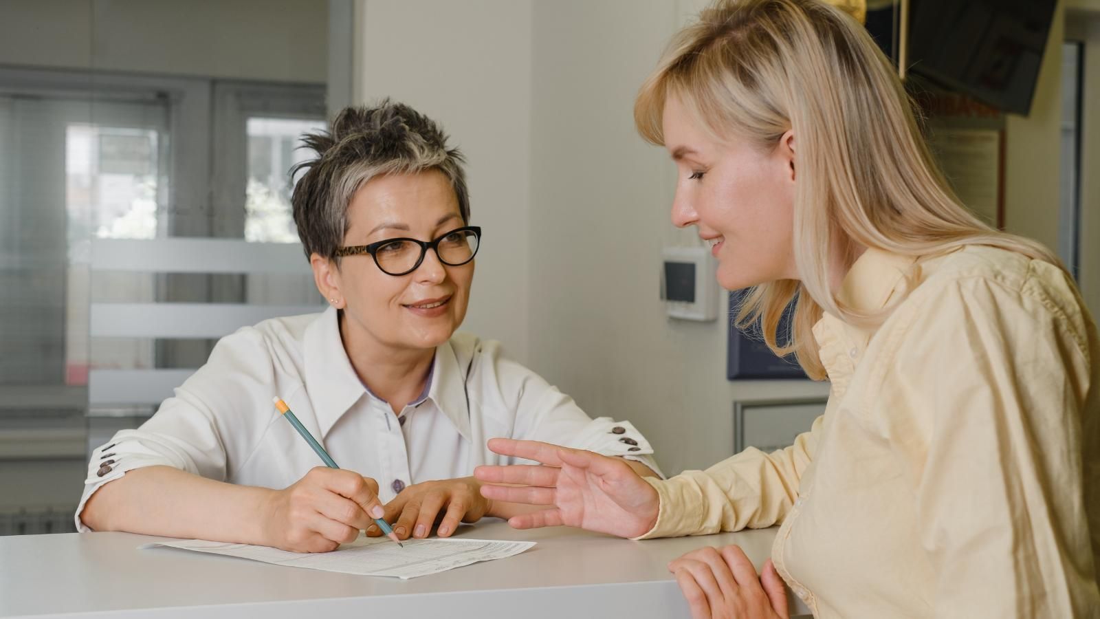 A doctor is sitting at a desk talking on a cell phone and scheduling a patients appointment.