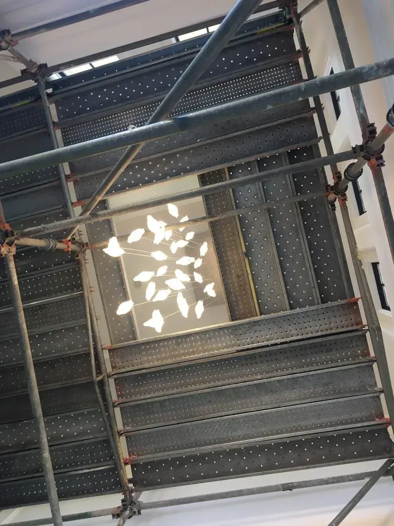 Scaffolding structure viewed from below, with a light pattern resembling leaves.