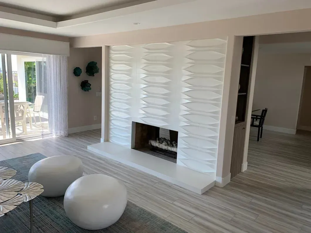 Living room with white fireplace, two white round ottomans, and sliding door to patio.