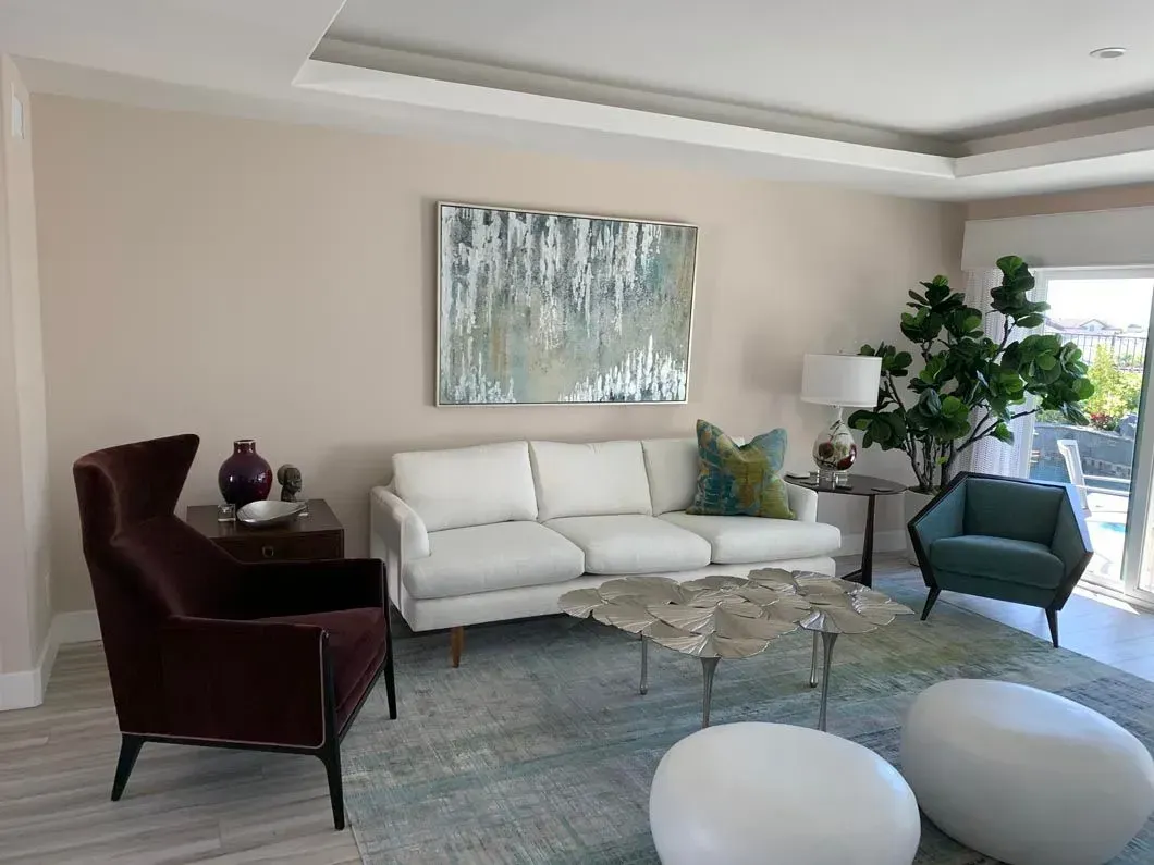 Living room with white sofa, artwork, teal chair, and rug.