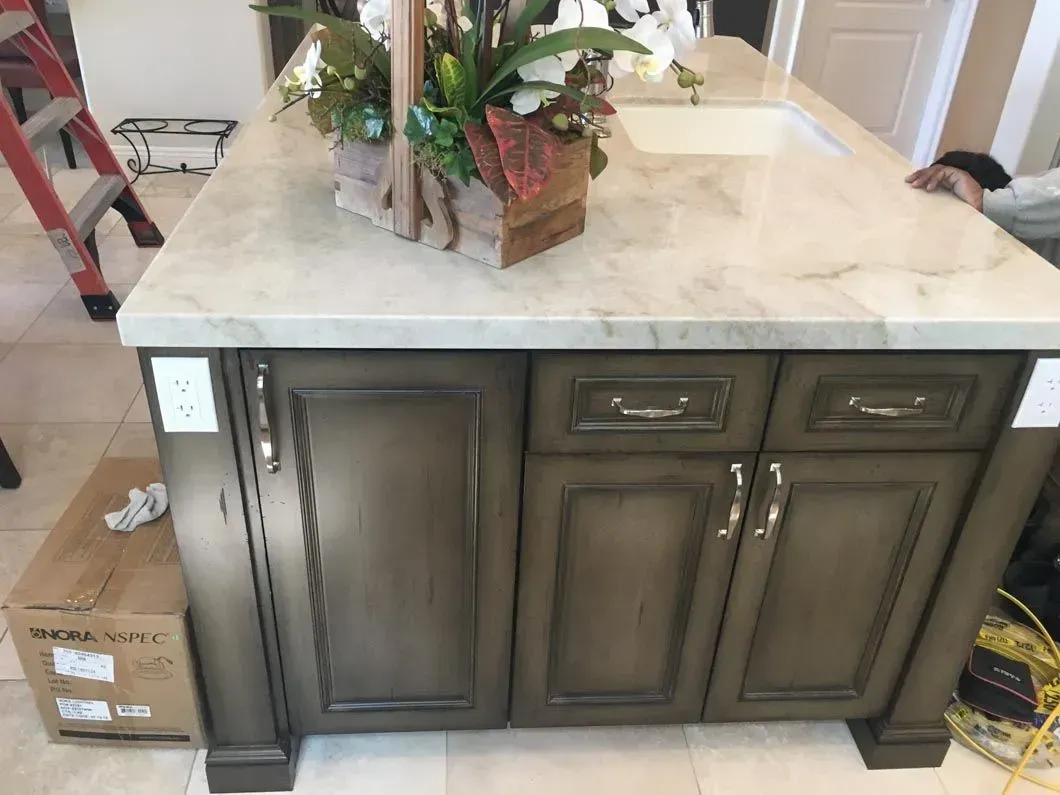 Kitchen island with gray cabinets, white countertop, and a floral arrangement.