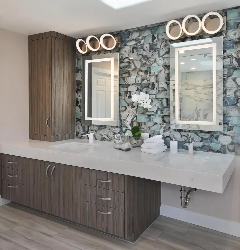 Bathroom with dual sinks, mirrors, and cabinetry, featuring a blue and white patterned accent wall.