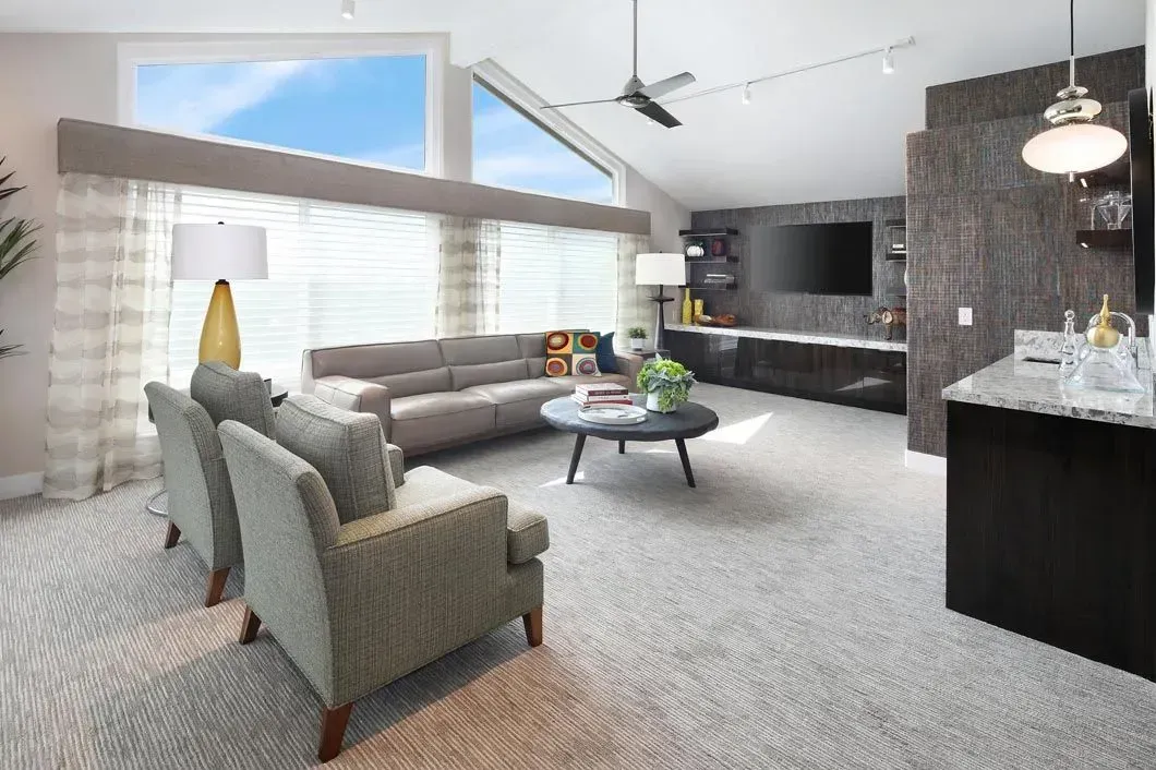 Living room with gray sofa, armchairs, coffee table, and large windows.