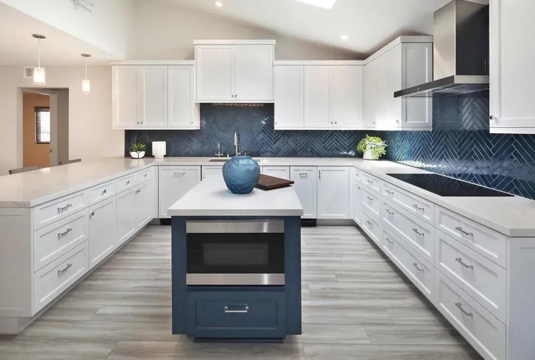 Modern kitchen with white cabinets, blue backsplash, and central blue island with microwave.